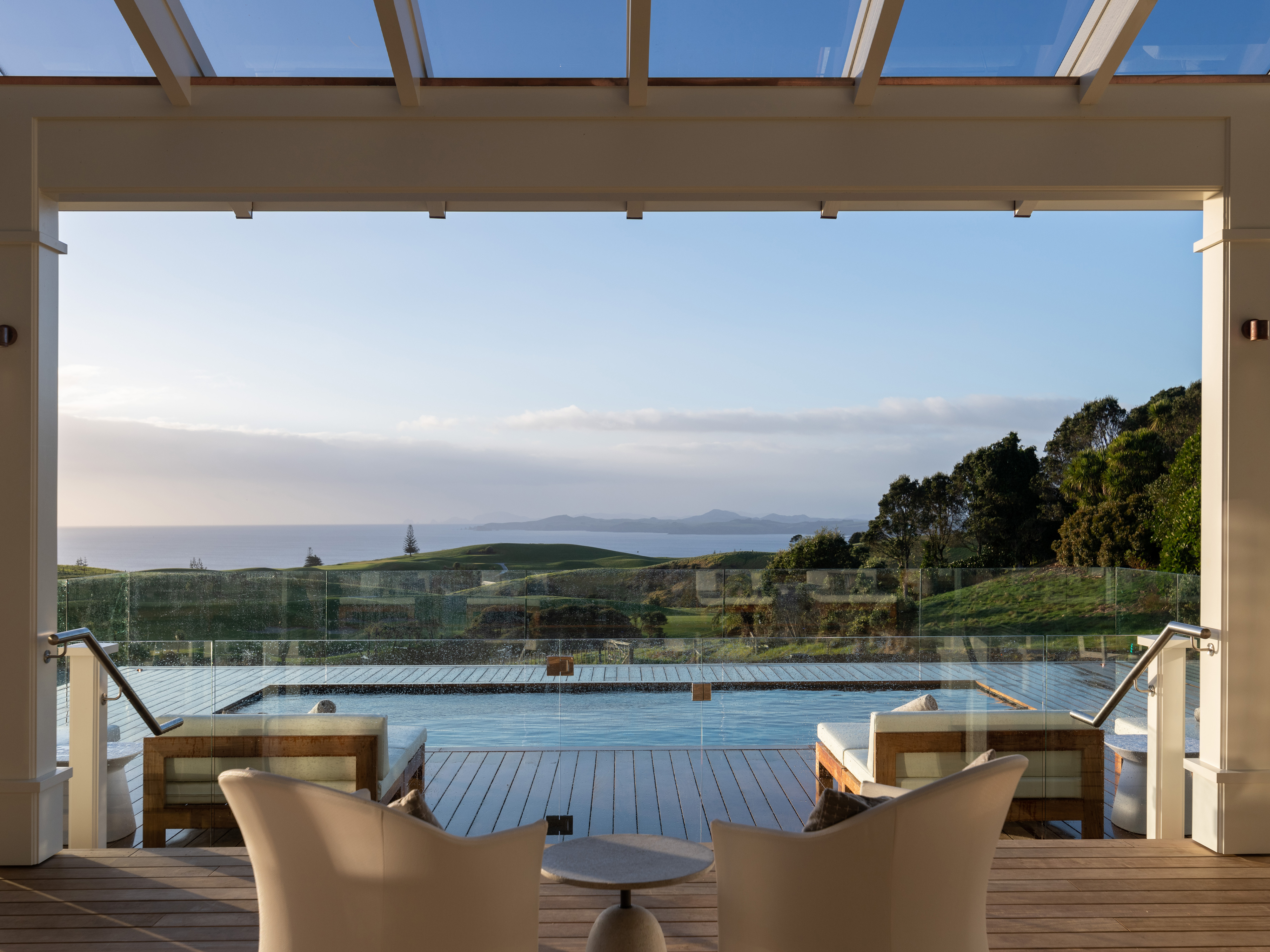 Luxury terrace with pool and loungers overlooking hills and distant ocean.